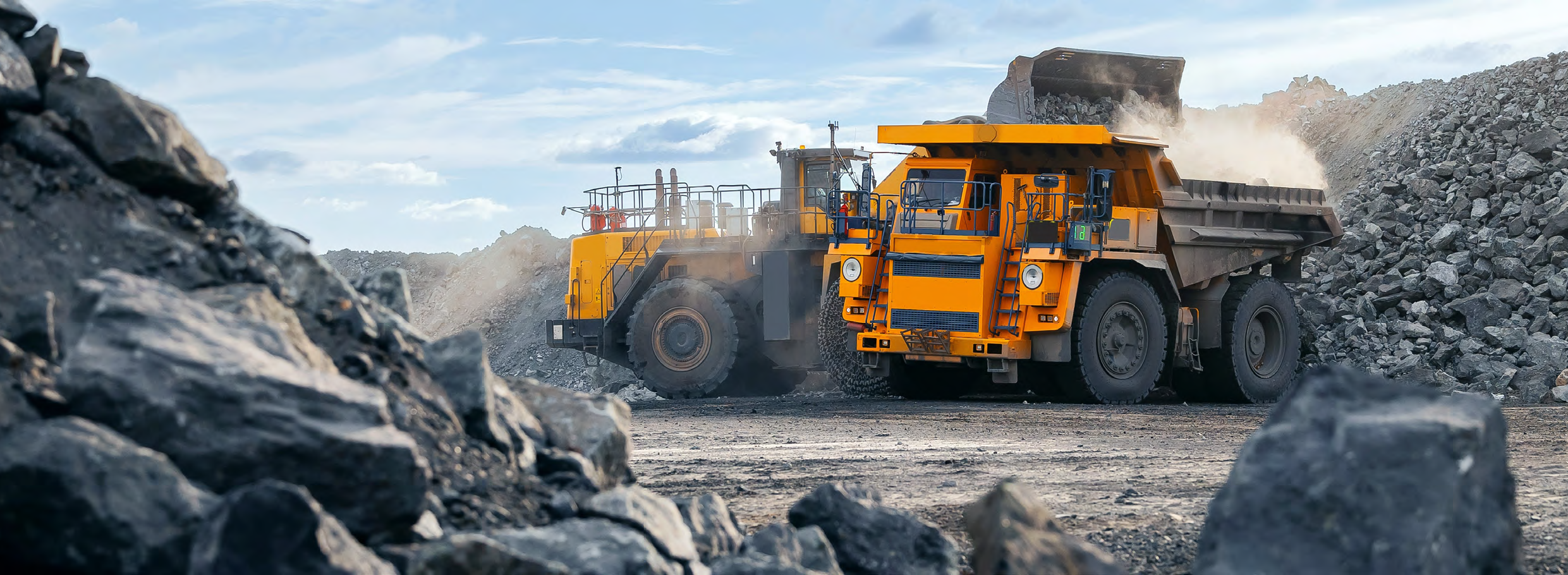 Excavator loading construction materials into quarry transport truck